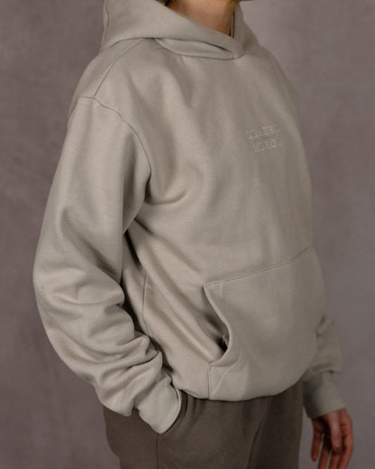 The Malla Hoodie in Natural Stone, side, worn by a 5ft 6 model in size Small